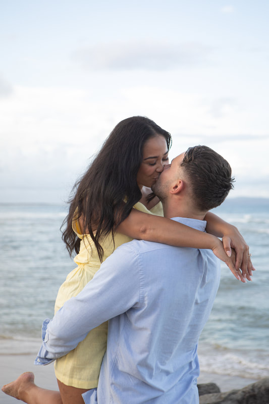 Couple on beach, just engaged and sharing a hug and a kiss